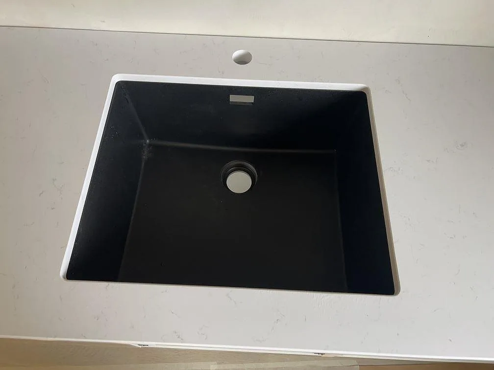 Underlimmad svart diskho i en polerad vit Technistone Noble Supreme White bänkskiva i ett kök i Malmö.