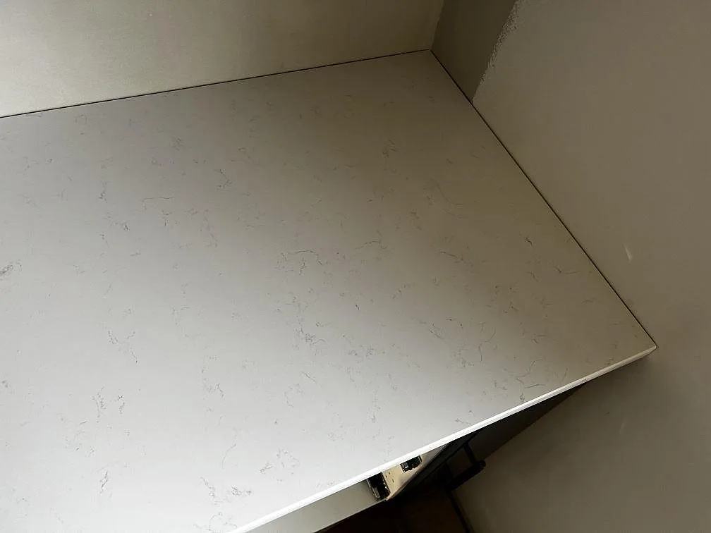 Närbild av ljus kompositbänkskiva i Technistone Noble Supreme White med diskret grå ådring vid vägg i Malmö.