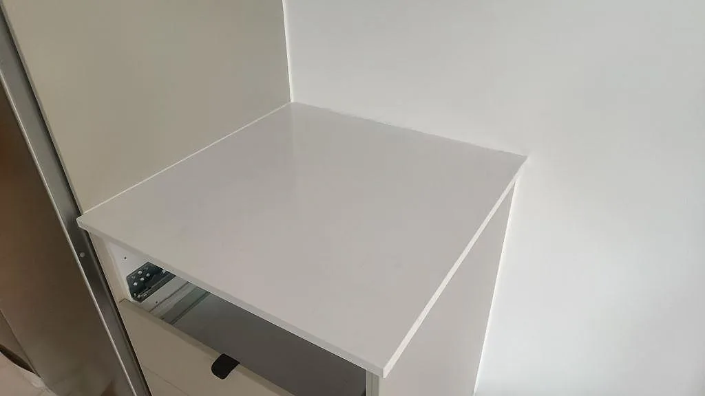 Separat vit bänkdel i polerad Technistone Noble Supreme White vid mörk träförvaring i Malmö.