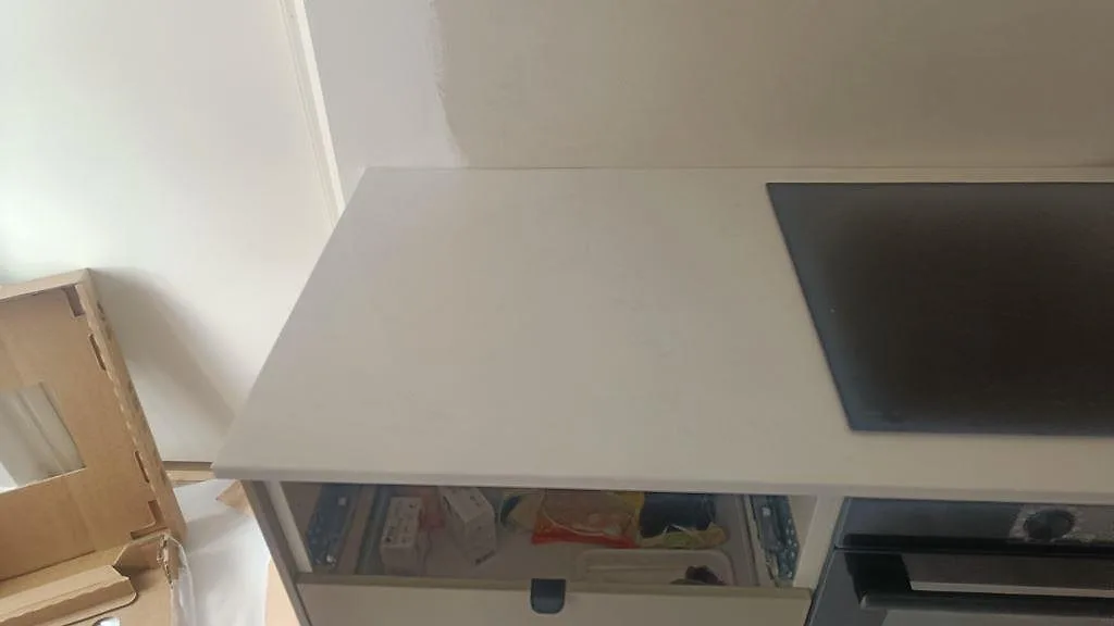 Närbild på vit Technistone Noble Supreme White bänkskiva, polerad, med svart häll och öppna köksstommar i Malmö.