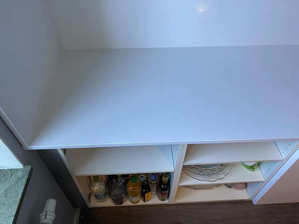 Vänstra delen av köksbänkskiva i Technistone Noble Supreme White med ljust stänkskydd och öppna stommar i Malmö.