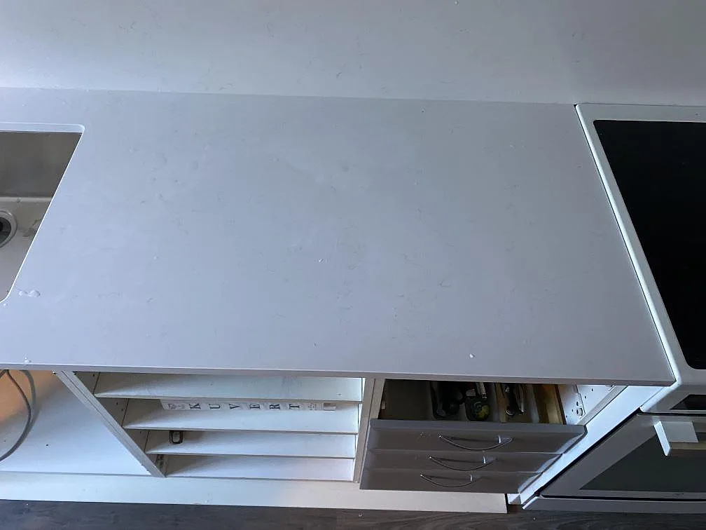 Detalj av polerad vit kompositbänkskiva i Technistone Noble Supreme White mellan diskho och spis i Malmö.