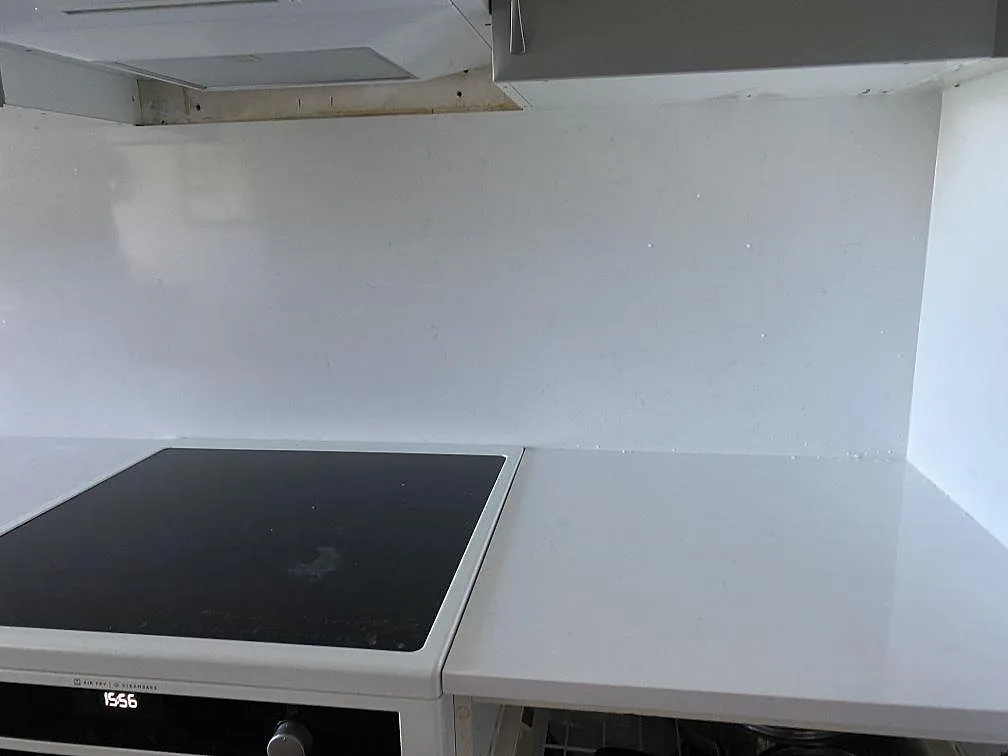 Polerad Technistone Noble Supreme White vid spis och stänkskydd, monterad som ljus köksbänkskiva i Malmö.