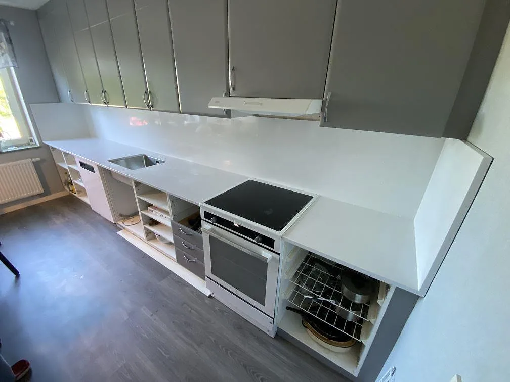 Köksbänkskiva i Technistone Noble Supreme White, polerad vit kvartskomposit, med rostfri diskho och stänkskydd i ett kök i Malmö.
