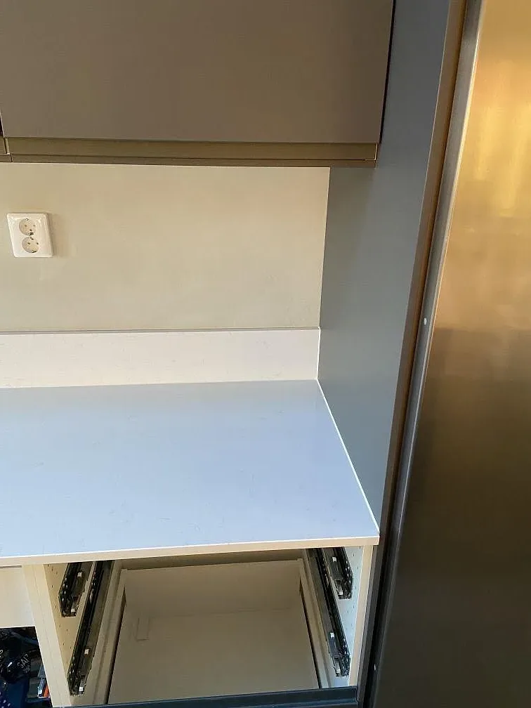 Vit Technistone Noble Supreme White som stänkskydd och vägghörn i ett kök under montering i Mörarp.