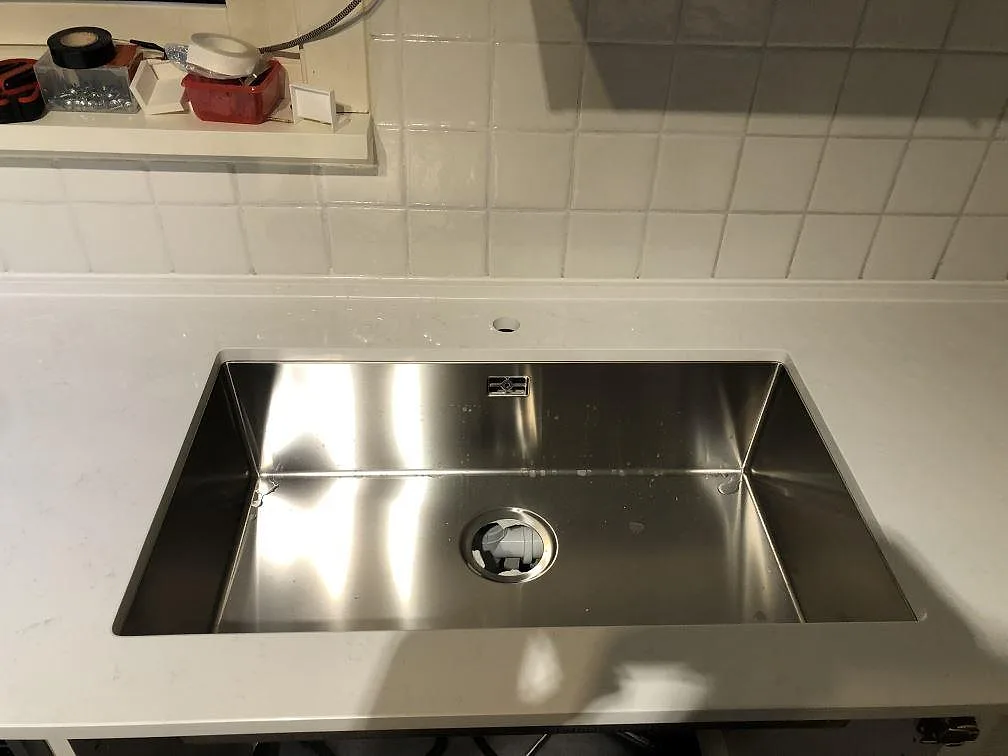 Stor underlimmad diskho i rostfritt stål i en vit Technistone Noble Supreme White köksbänkskiva i Sävedalen.