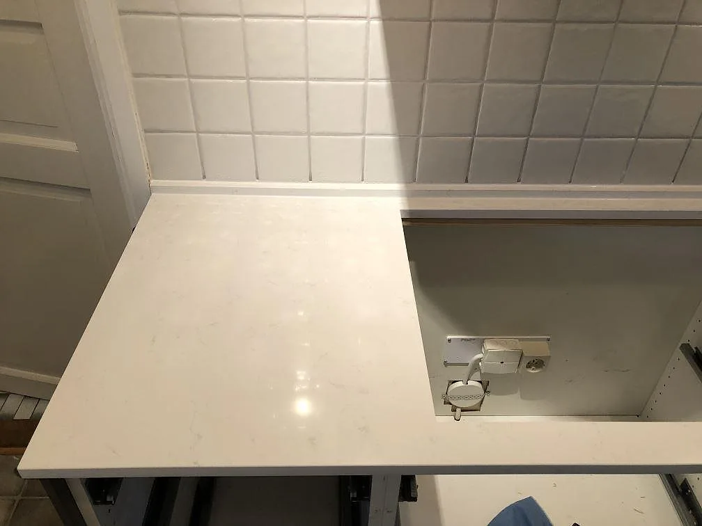 Vit köksbänkskiva i Technistone Noble Supreme White med urtag för diskho mot vitt kakel i ett kök i Sävedalen.