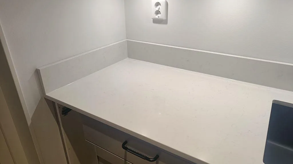 Närbild på vit Technistone Noble Supreme White komposit med uppvikt stänkkant och underlimmad diskho i ett kök i Skegrie.