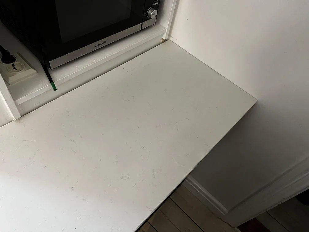 Sidoyta i polerad Technistone Noble Supreme White komposit intill vägg och fönsternisch i ett kök i Trelleborg.
