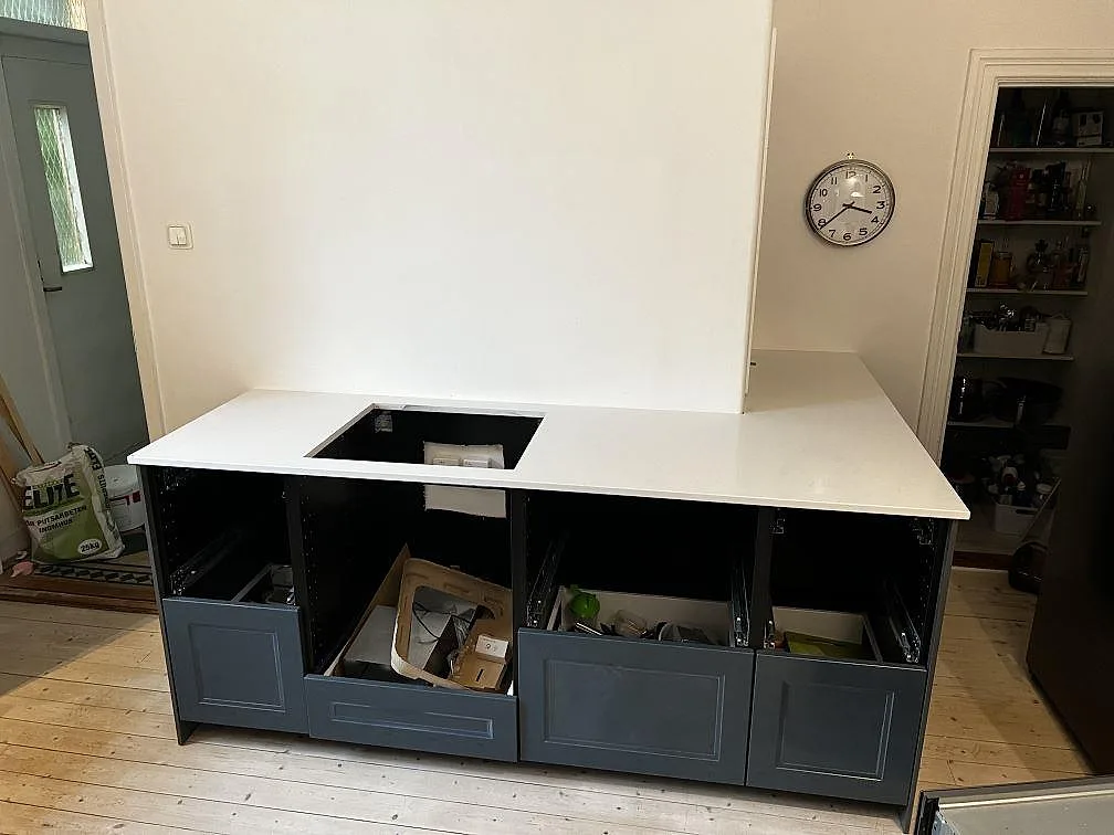 Installerad köksbänkskiva i Technistone Noble Supreme White, polerad vit komposit, på grå köksstommar med hällöppning i Trelleborg.