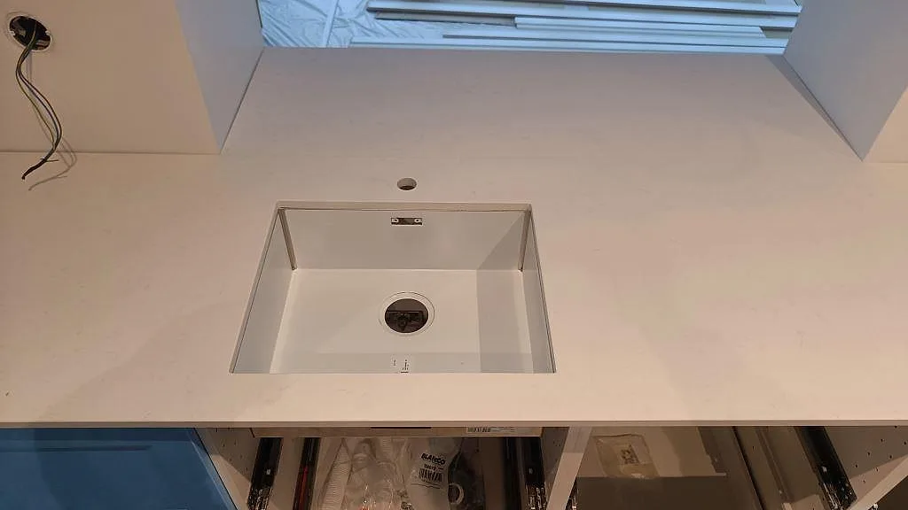 Närbild ovanifrån på underlimmad diskho i vit Technistone Noble Supreme White köksbänkskiva i Tygelsjö.