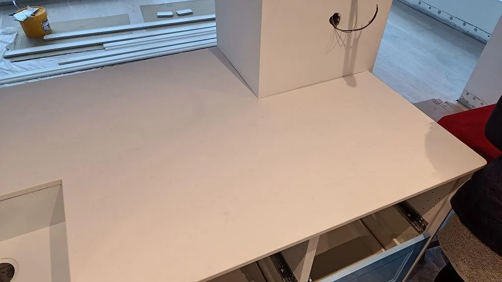 Hörnparti av köksbänkskiva i vit Technistone Noble Supreme White med diskret ådring i ett kök under montering i Tygelsjö.