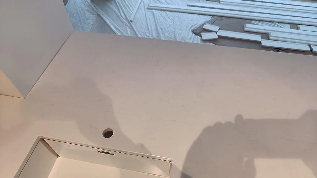 Köksbänkskiva i vit Technistone Noble Supreme White med blandarhål sett ovanifrån i ett kök i Tygelsjö.
