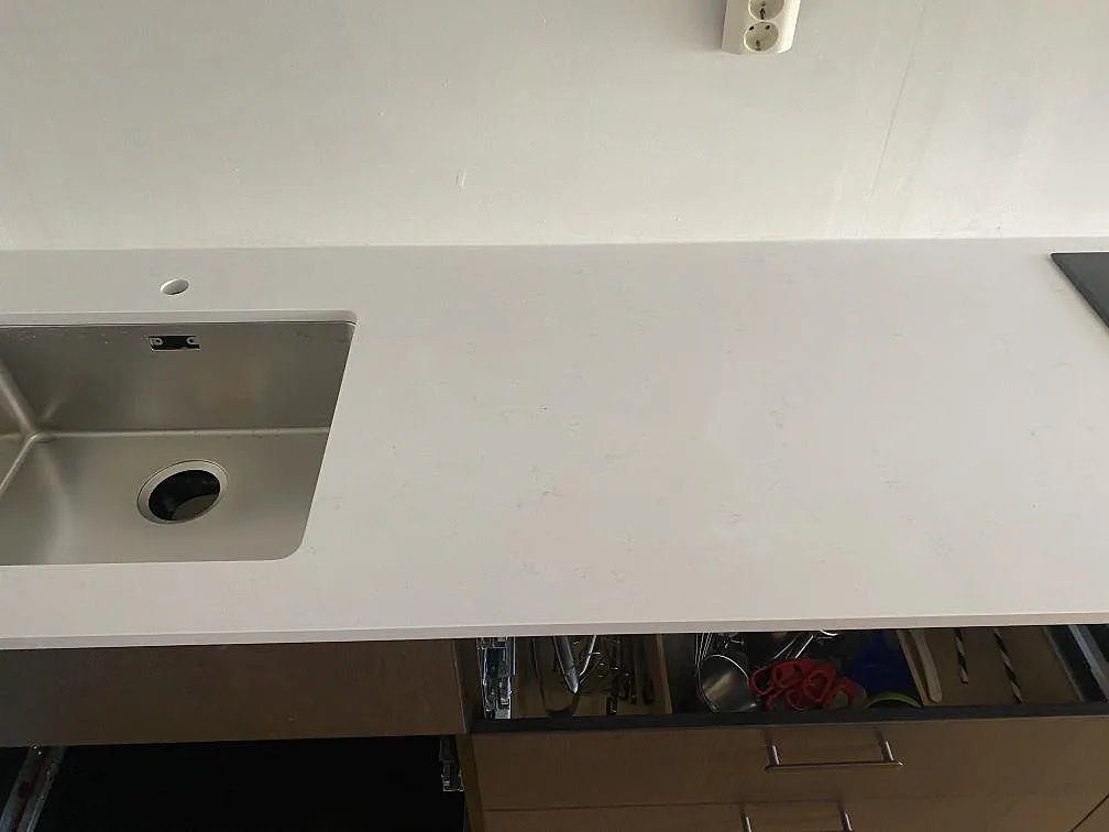 Infälld induktionshäll i en vit köksbänkskiva av Technistone Noble Supreme White i ett kök i Västra Frölunda.