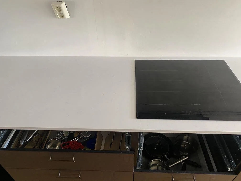 Lång köksbänkskiva i vit Technistone Noble Supreme White med infälld induktionshäll i Västra Frölunda.