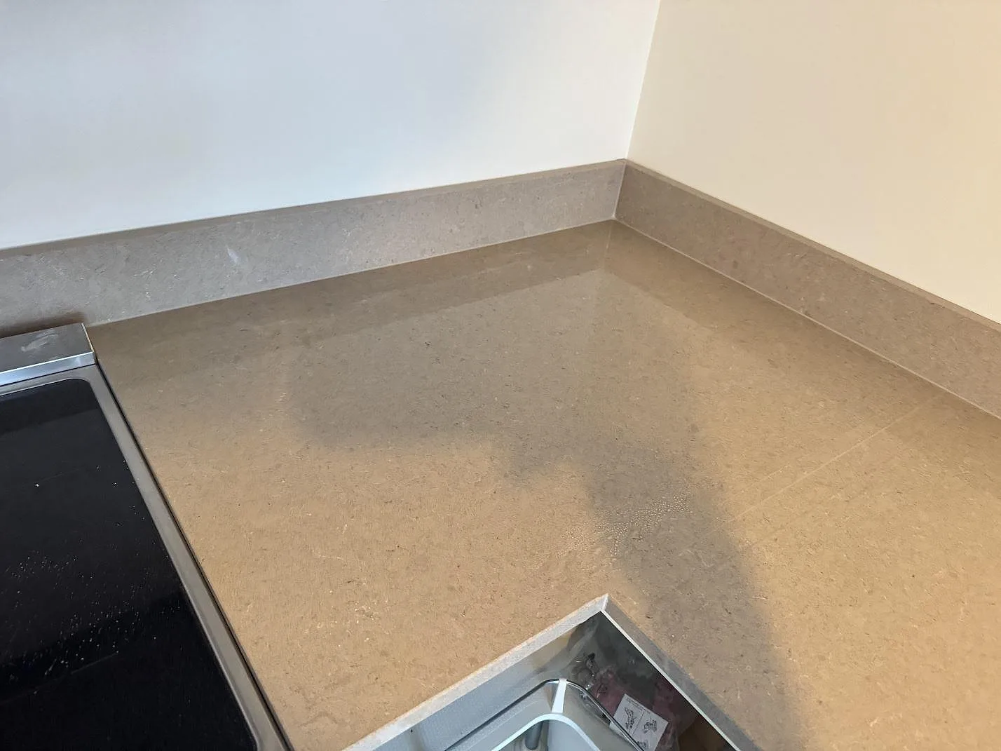 Detalj av polerad köksbänkskiva i Technistone Noble Troya med spis, hörnsektion och uppvikt stänkkant i Göteborg.