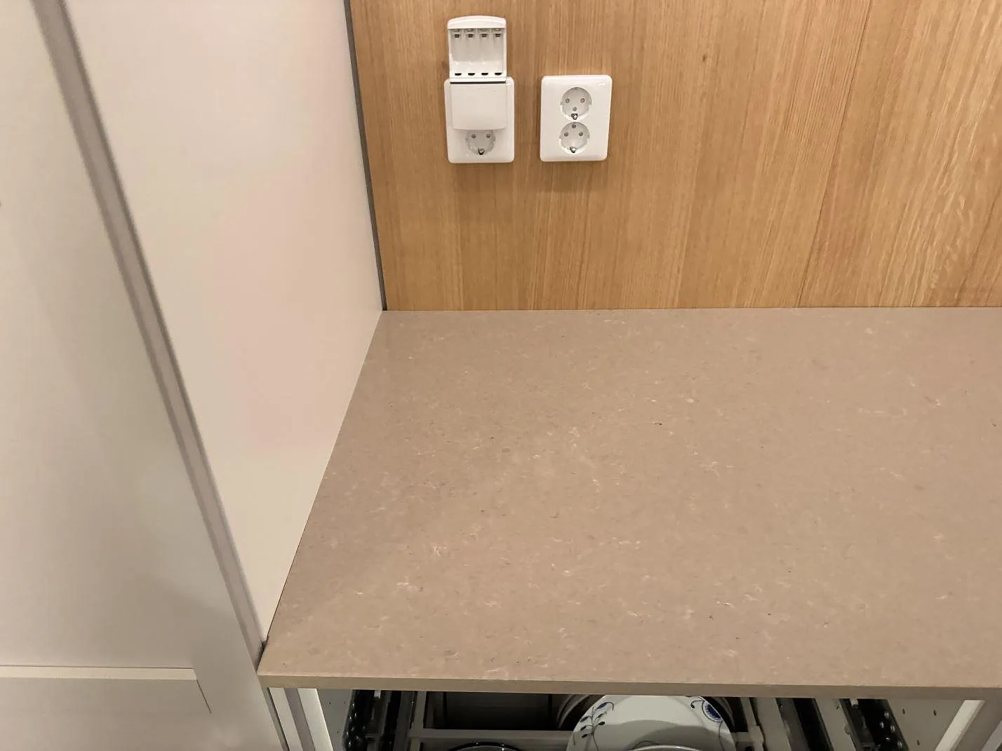 Installerad köksbänkskiva i polerad Technistone Noble Troya vid vägguttag och träpanel i Löddeköpinge.