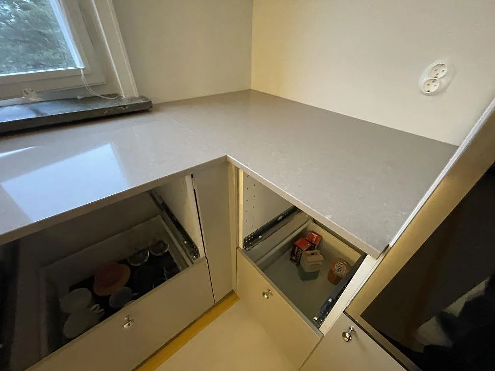 Hörndel av polerad Technistone Noble Troya köksbänkskiva med grå kompositstruktur och öppna stommar i Stockholm.