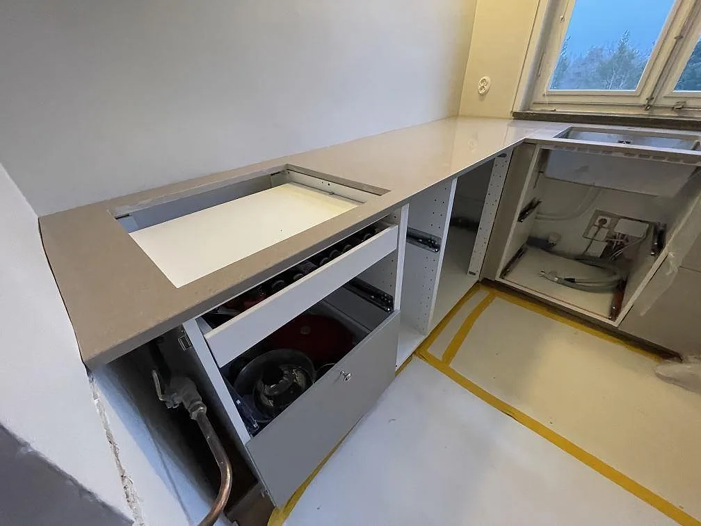 Köksbänkskiva i Technistone Noble Troya med synlig hällöppning och diskhozon i ett kök under montering i Stockholm.