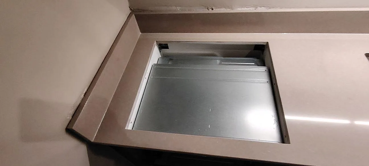 Detalj av hällöppning i polerad Technistone Noble Troya med stänkkant och ljus komposityta i Sundbyberg.