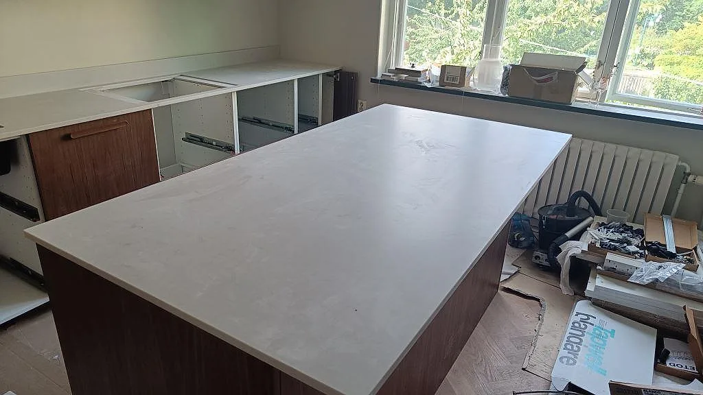 Stor köksö med bänkskiva i matt Technistone Noble Villa och samma ljusa komposit längs väggen i Göteborg.
