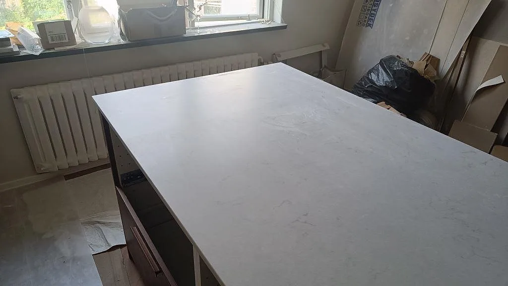 Närbild av köksöns ljusa komposityta i matt Technistone Noble Villa med diskret grå ådring i Göteborg.