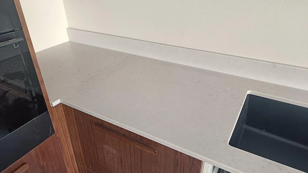 Väggmonterad köksbänkskiva i matt Technistone Noble Villa med låg stänkkant och svart diskho i Göteborg.