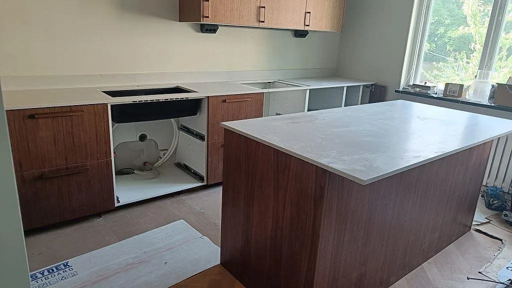 Köksbänkskiva i matt Technistone Noble Villa med köksö, väggbänk och ljus stänkkant i ett kök i Göteborg.