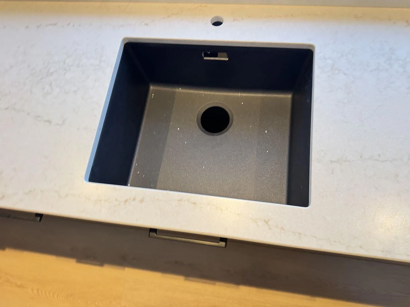 Underlimmad svart kompositdiskho infälld i matt Technistone Noble Vintage, sedd ovanifrån, i ett kök i Glostrup.