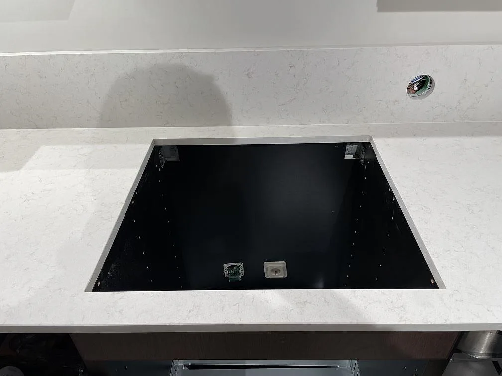 Ovanifrån av urtaget för induktionshällen i en matt Technistone Noble Vintage köksbänkskiva, med synlig diskret marmorådring, i ett kök i Hägersten.