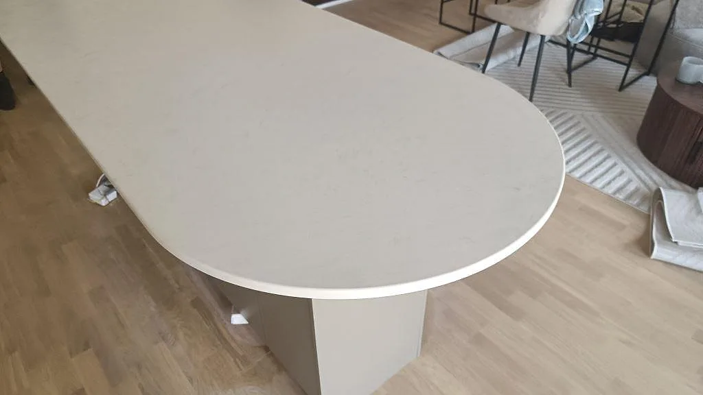 Närbild på rundad kortsida på köksö i matt Technistone Noble Vintage komposit i ett kök i Hovås.