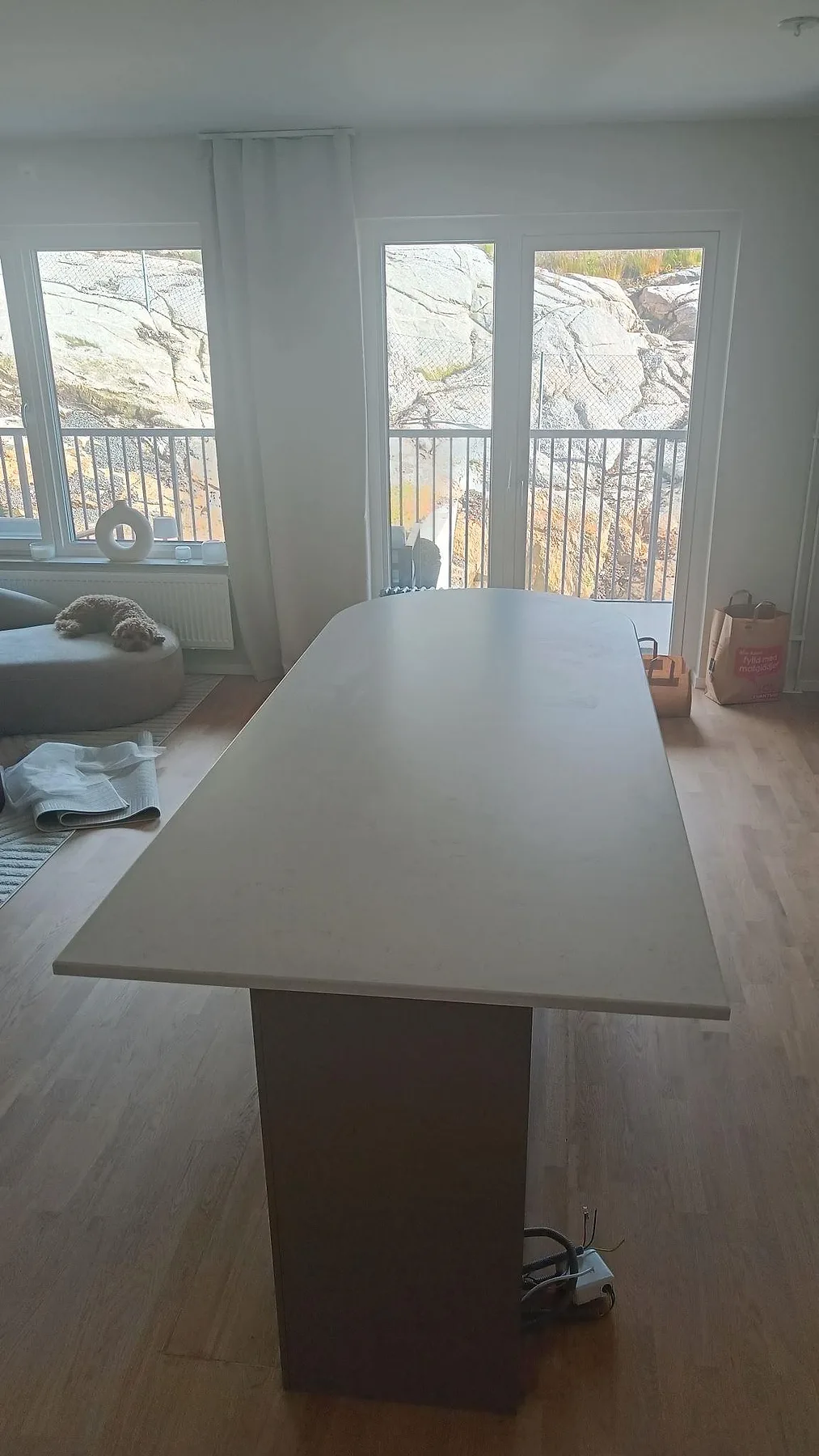 Lång köksö i matt Technistone Noble Vintage komposit framför fönster och vardagsrumsdel i Hovås.