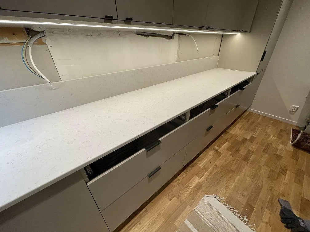Lång obruten bänkrad i matt Technistone Noble Vintage med diskret grå ådring längs väggen i ett kök i Stockholm.