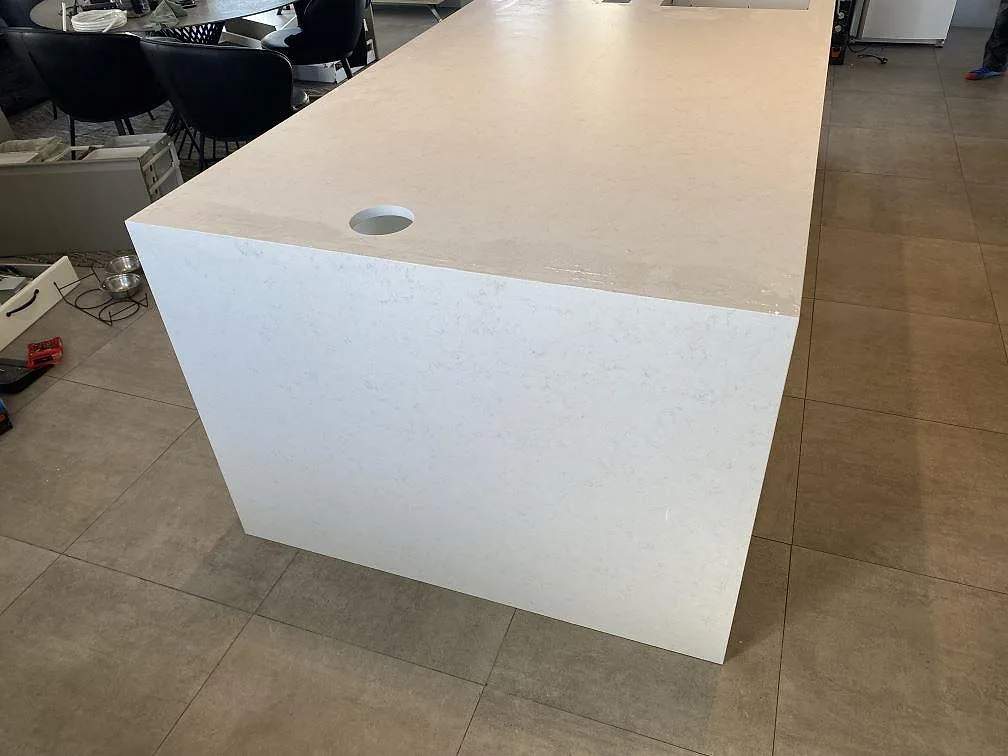 Sidovy av köksö i Technistone Noble Vintage, matt ljus kvartskomposit, med rund genomföring och neddragen stengavel i Trelleborg.