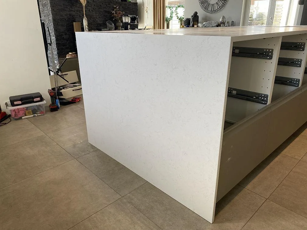 Installerad köksö i Technistone Noble Vintage, matt 20 mm kvartskomposit, med öppen köksstomme och ljus stengavel i Trelleborg.