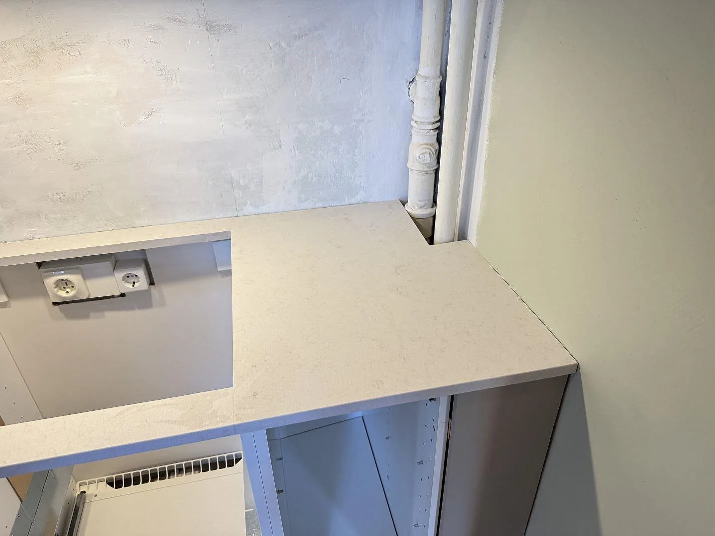 Detalj av installerad Technistone Noble Vintage bänkskiva, matt kvartskomposit 20 mm, vid vägg och köksstommar i Trelleborg.