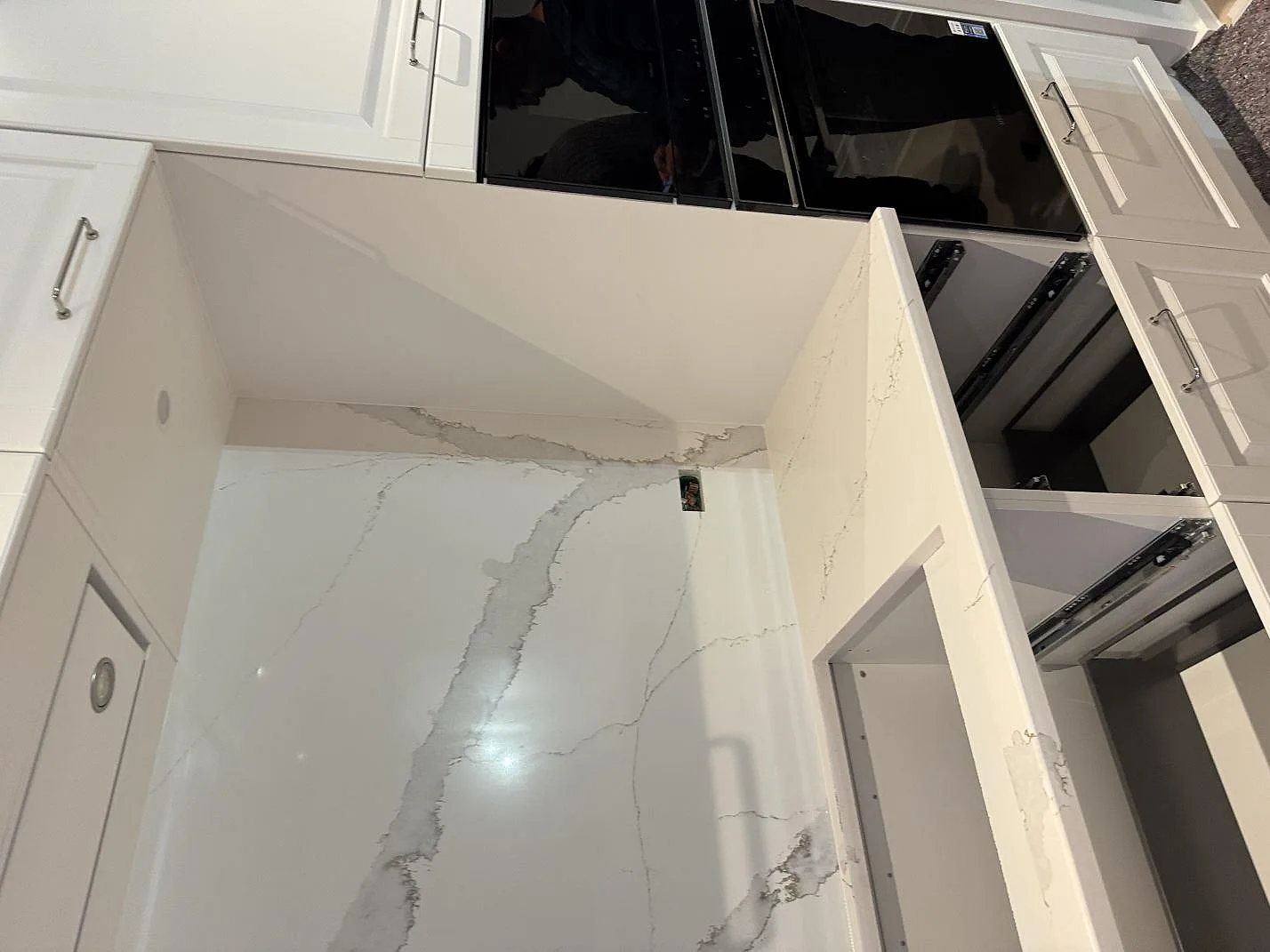 Induktionshäll monterad ovanpå en köksbänkskiva i Technistone Volegno med stänkskydd i samma vita komposit, i ett kök i Skovlunde.