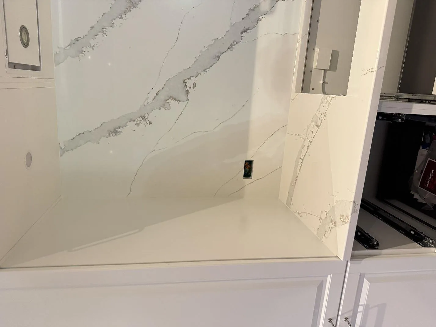 Köksbänkskiva i Technistone Volegno med polerad yta och grå ådring längs en bänkrad med stänkskydd, i ett kök under montering i Skovlunde.