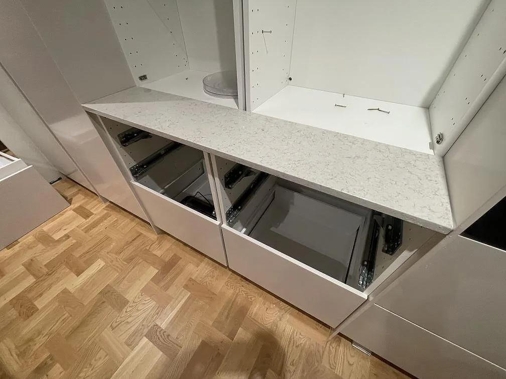 Detalj av köksö i Technistone Wild Yucca, varmvit kvartskomposit med grått stänk, ovanför öppna skåpsstommar i ett kök i Karlstad.