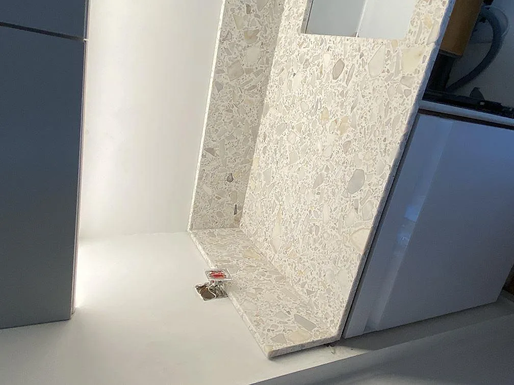 Vit Terazzo Calacatta bänkskiva med stänkkant installerad mot vägg i ett kök under montering i Staffanstorp.