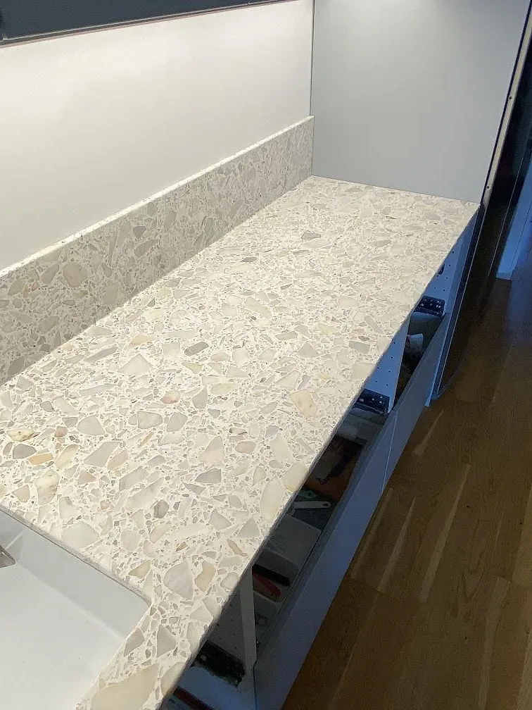 Närbild på den matta vita terrazzon med ljusa marmorflisor på en köksbänkskiva i Staffanstorp.