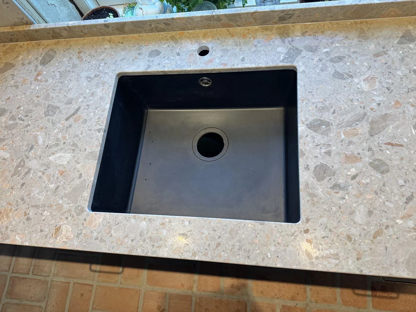 Detalj av svart diskho i en matt köksbänkskiva i Terrazzo Breccia Oniciata med beige terrazzo i Tomelilla.