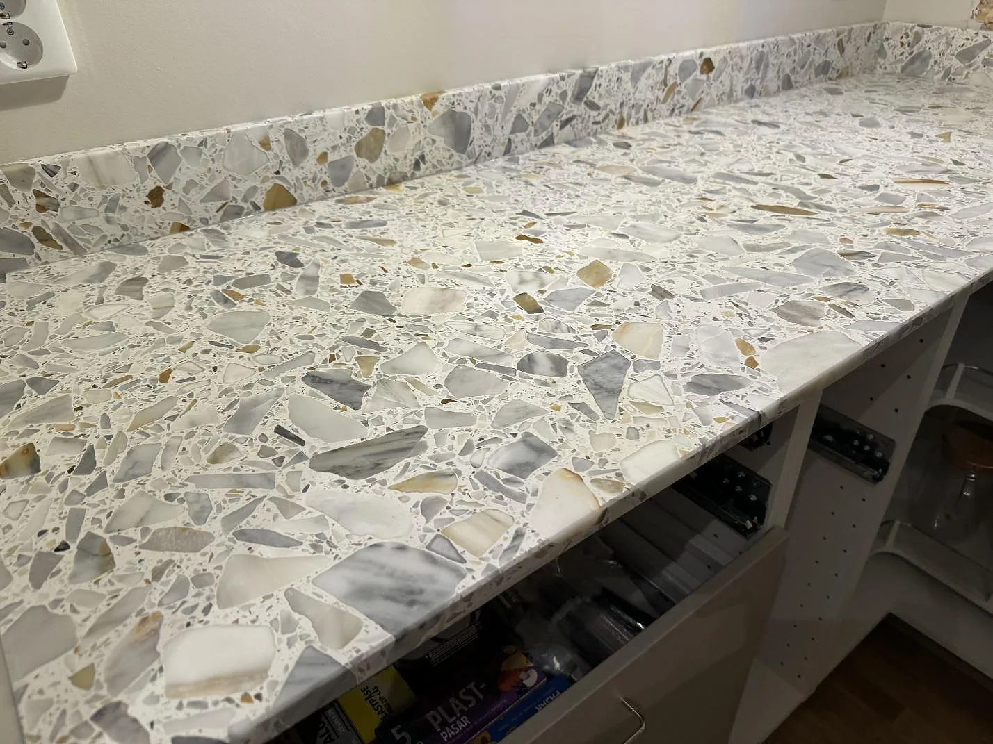 Närbild på matt Terrazzo Calacatta-bänkskiva med stora grå och guldtonade fragment i kök i Förslöv.