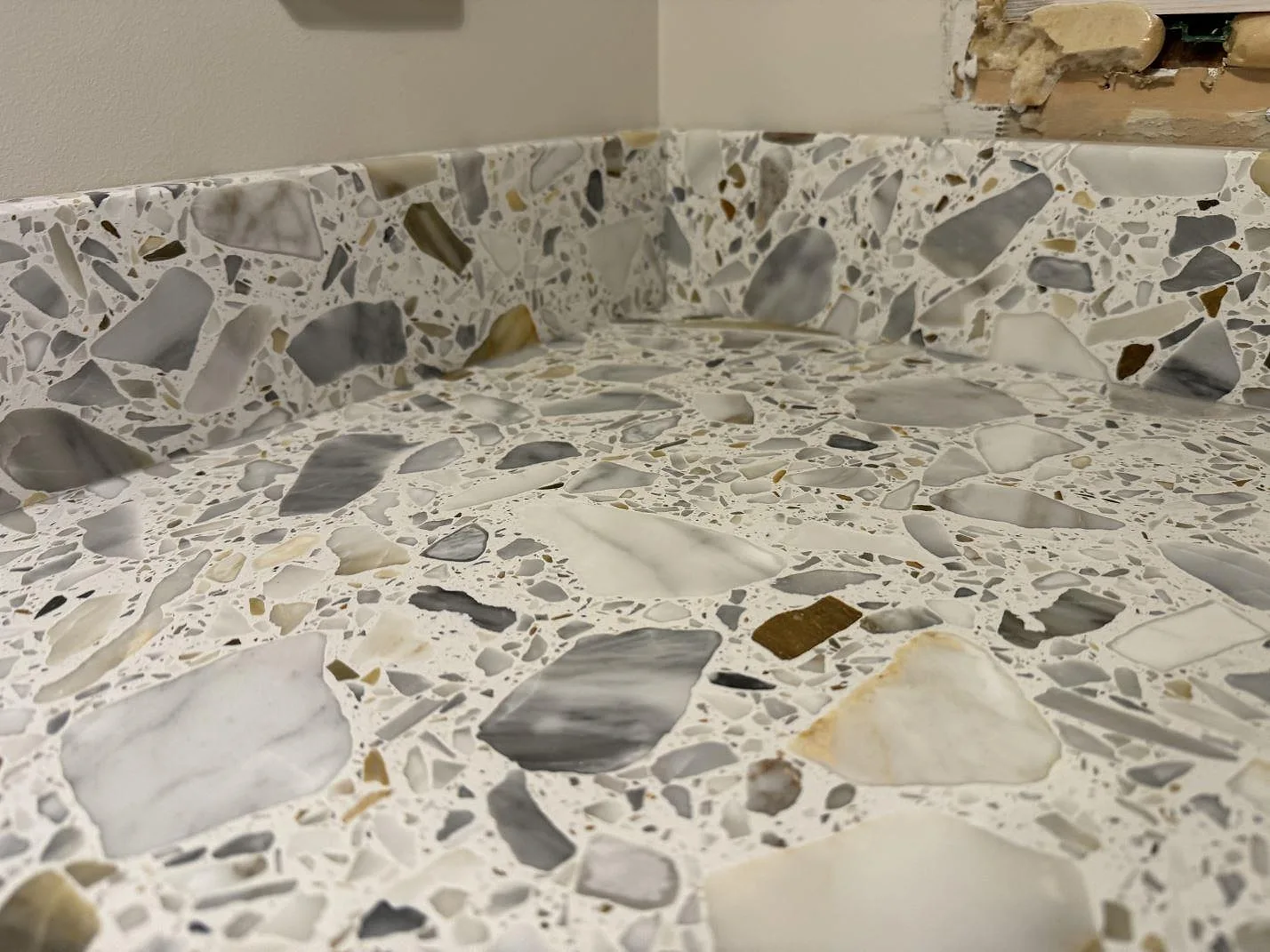 Närbild på stänkkant och bänkyta i matt Terrazzo Calacatta med tydliga marmorfragment i Förslöv.