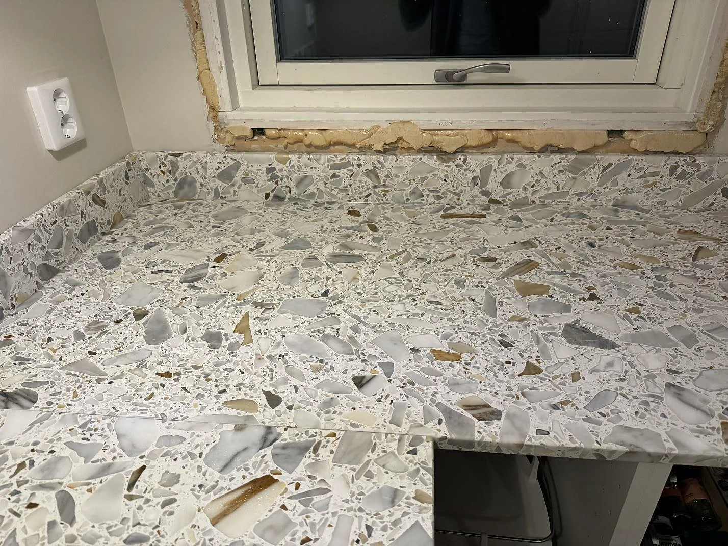 Köksbänkskiva i matt Terrazzo Calacatta framför fönster med matchande stänkkant i Förslöv.