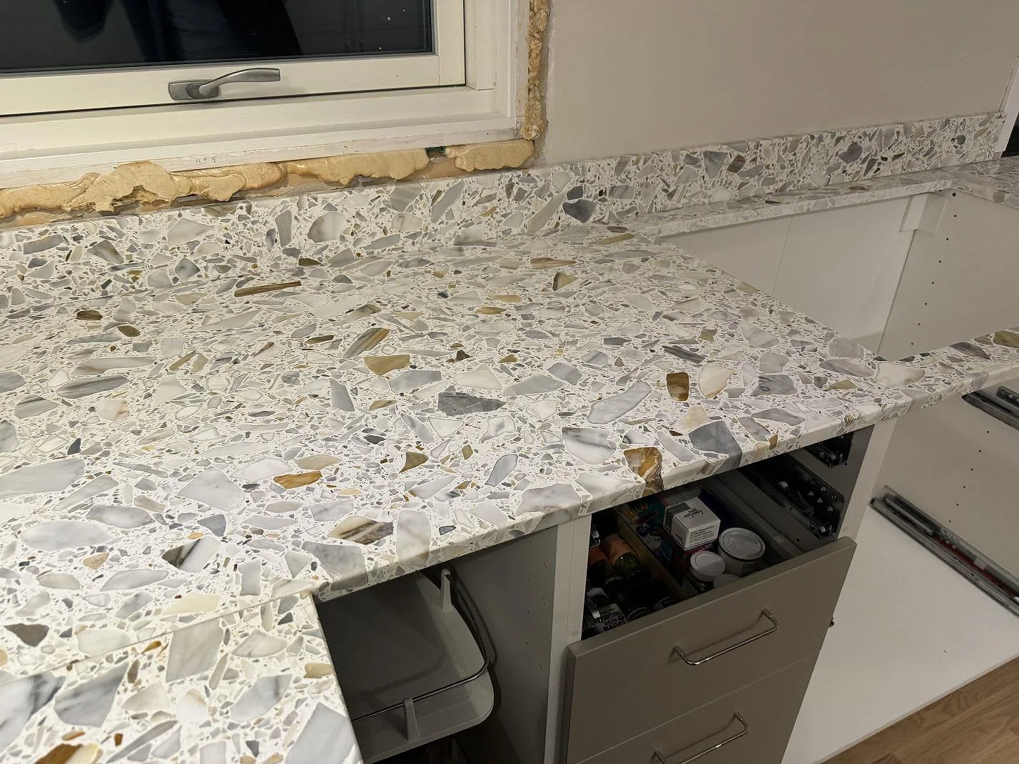 Matt Terrazzo Calacatta-bänkskiva med stänkkant under fönster, monterad på vita köksstommar i Förslöv.