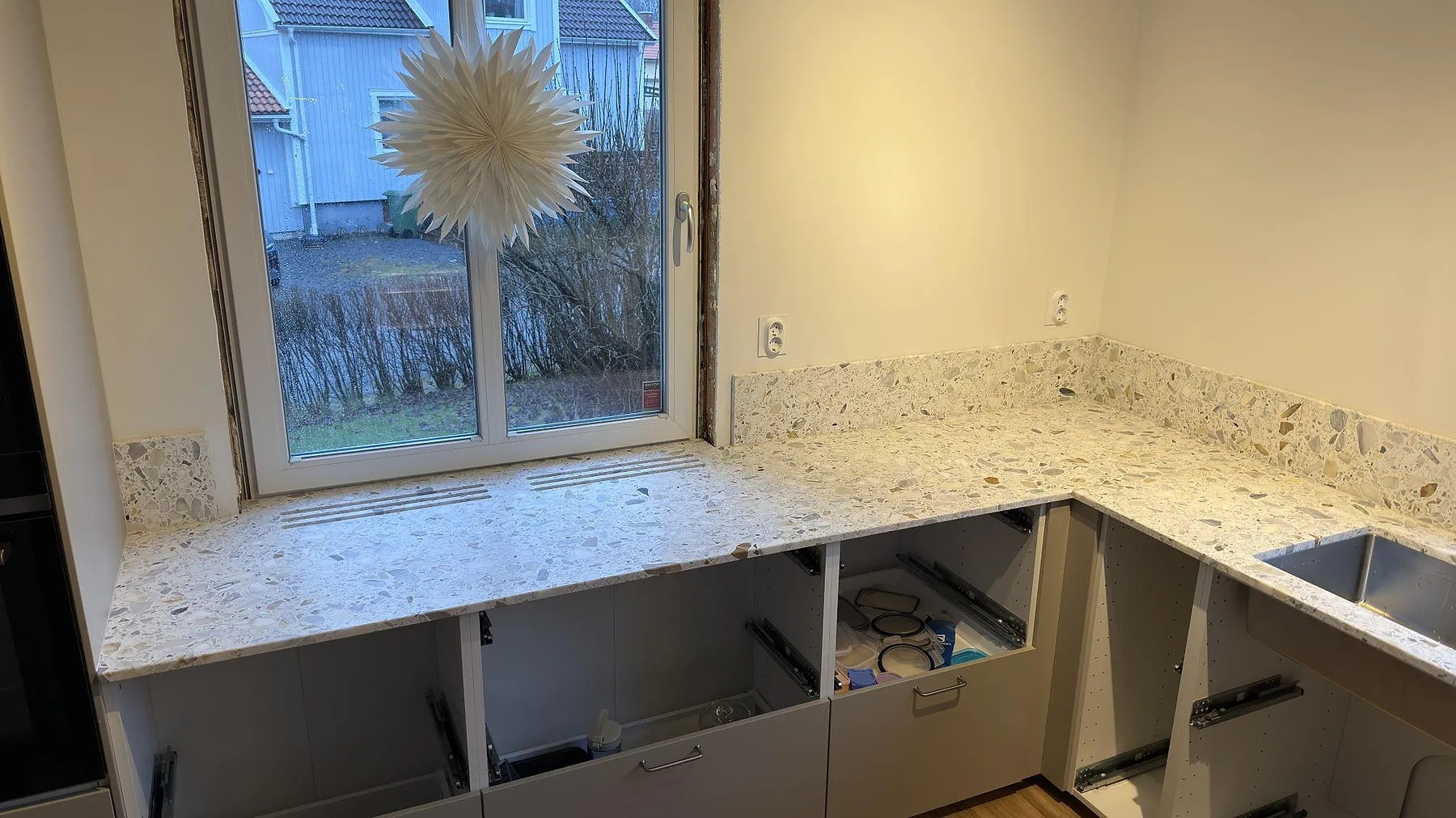 Köksbänkskiva i Terrazzo Calacatta med matchande fönsterbänk i samma terrazzo vid köksfönstret i ett kök i Karlskoga.