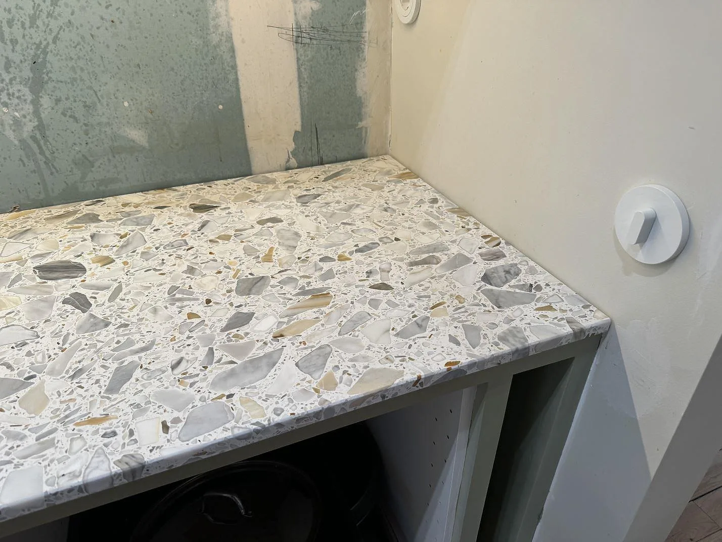 Detalj av matt Terrazzo Calacatta vid höger bänkskiveände med öppna köksstommar i Kode.
