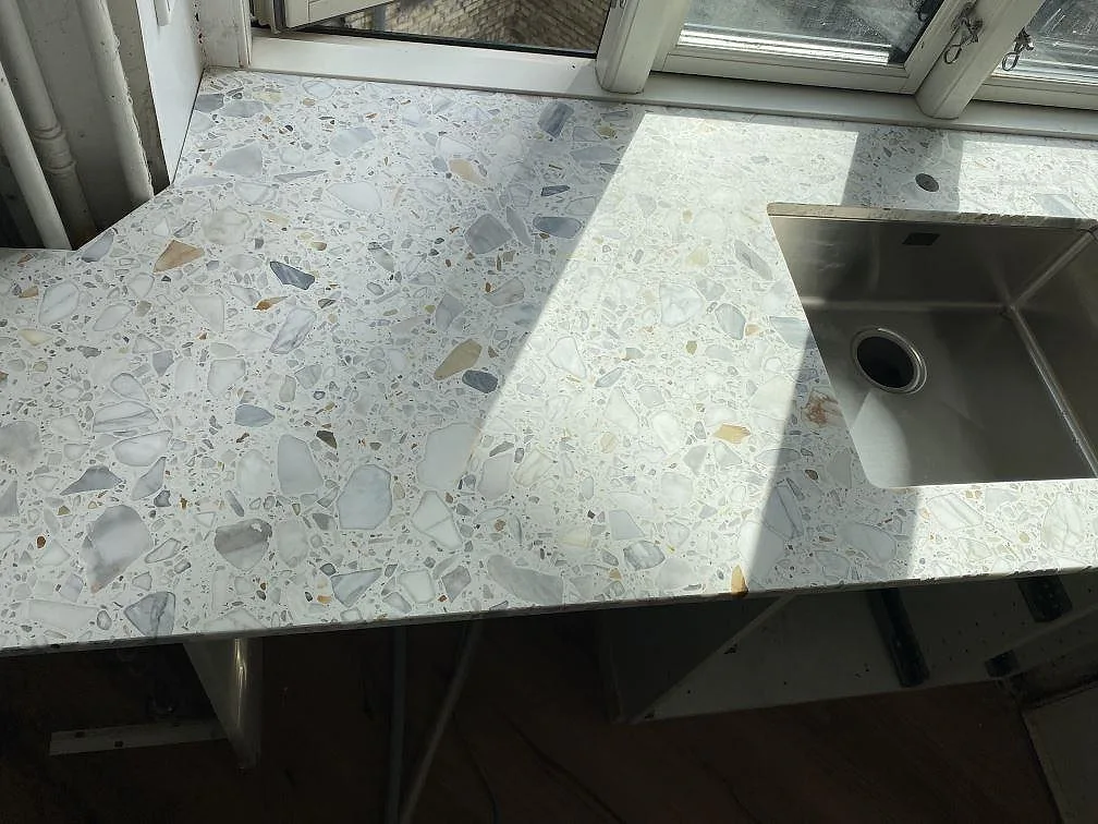 Topvy över matt Terrazzo Calacatta med stora ljusa stenfragment och diskho under montering i København Ø.