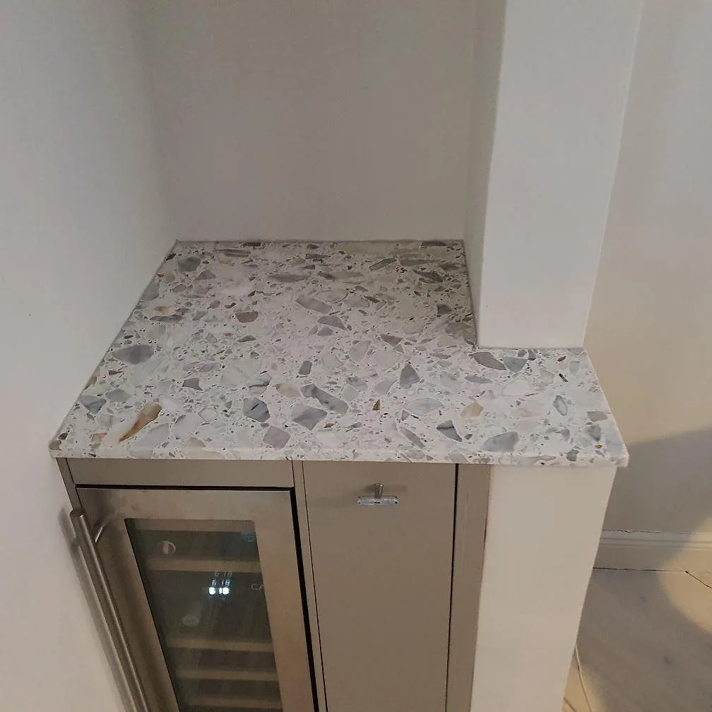 Närbild på matt Terrazzo Calacatta som bänkskiva över skåp och vinkyl i ett kök i Stockholm.
